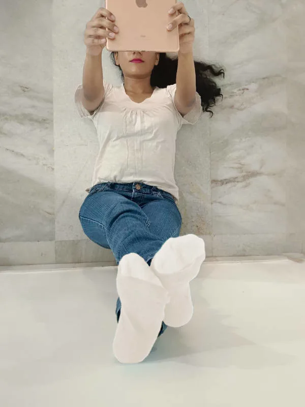 Brand and web designer holding an iPad with her leg resting on the wall